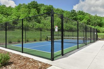 A tennis court is enclosed by a black fence.